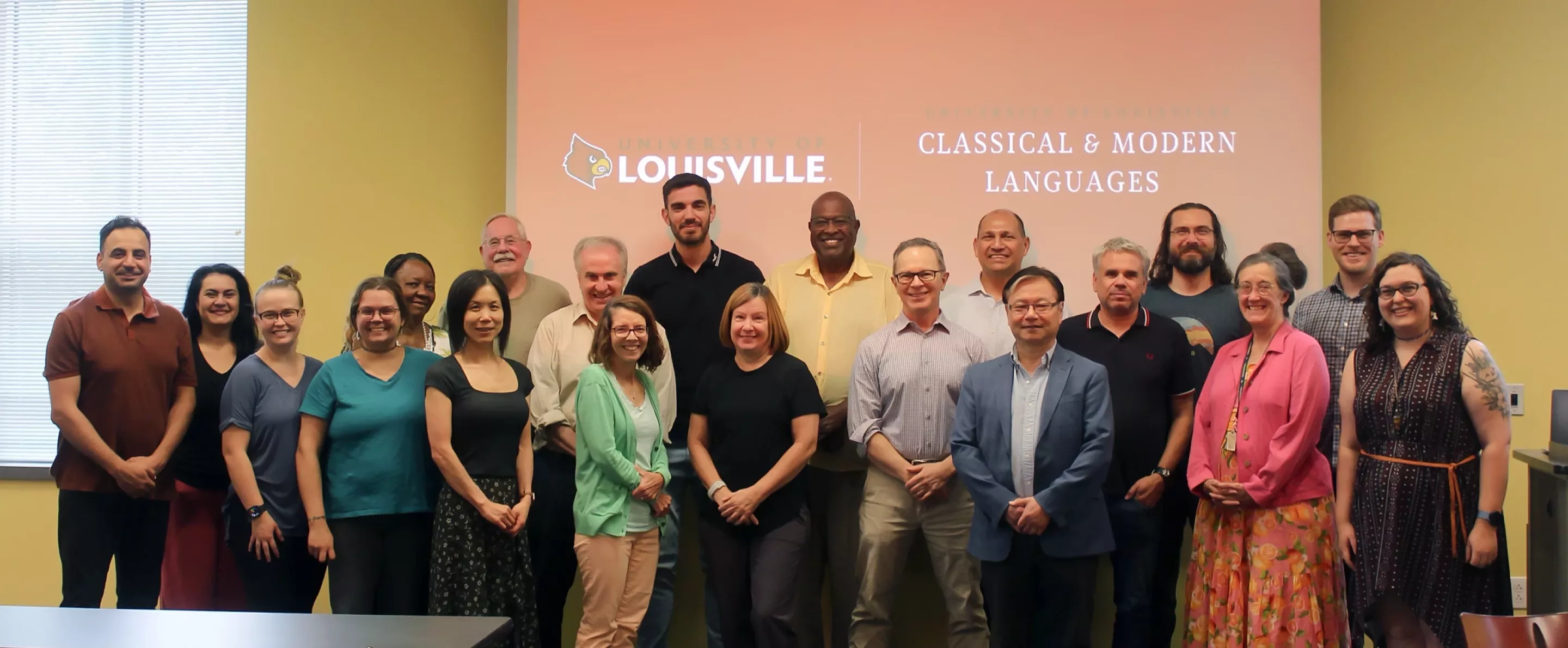 CML Faculty and Staff stands in front of a presentation screen displaying "Classical & Modern Languages" at the University of Louisville.