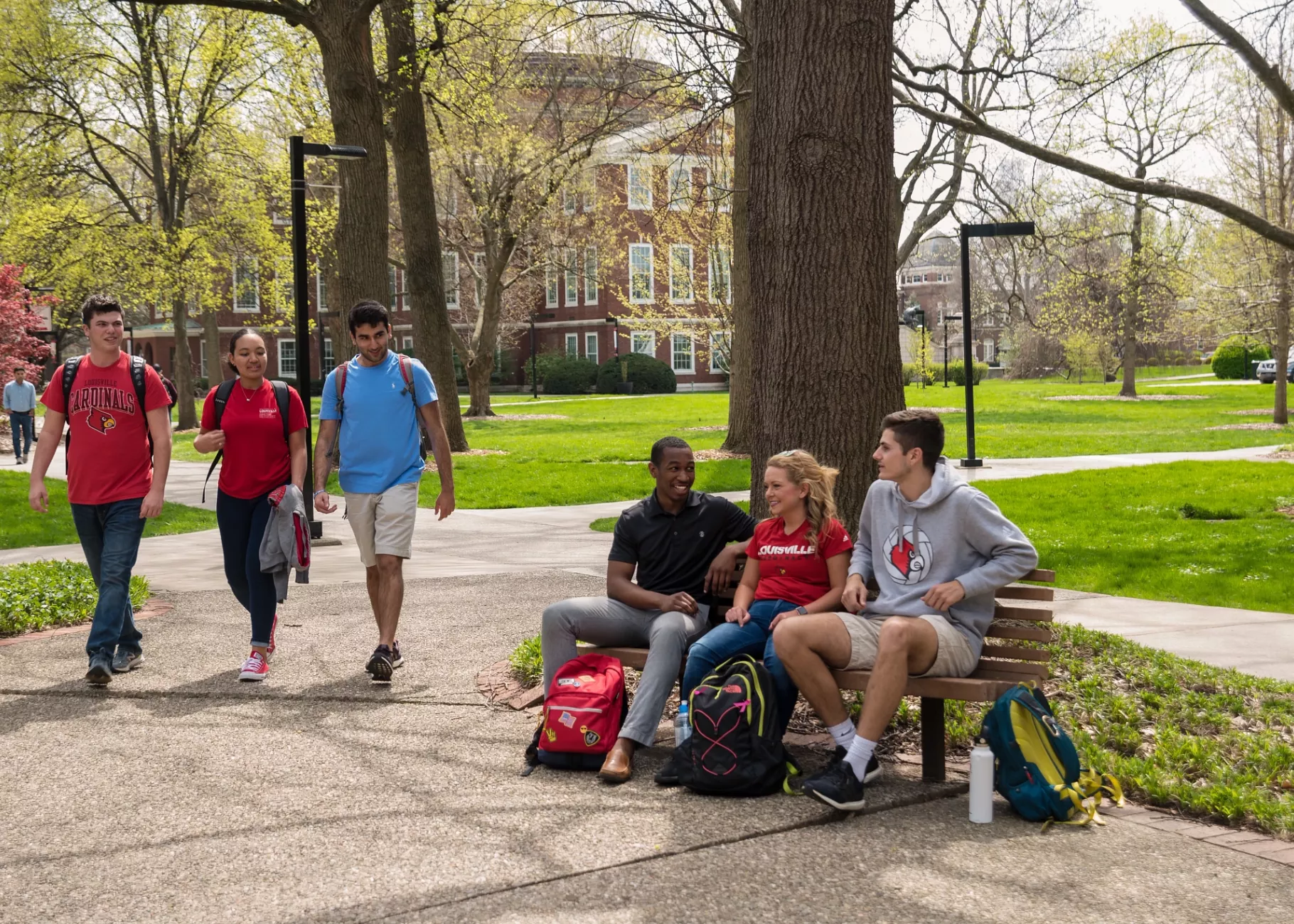 Three students walking past three seated students on Belknap Campus