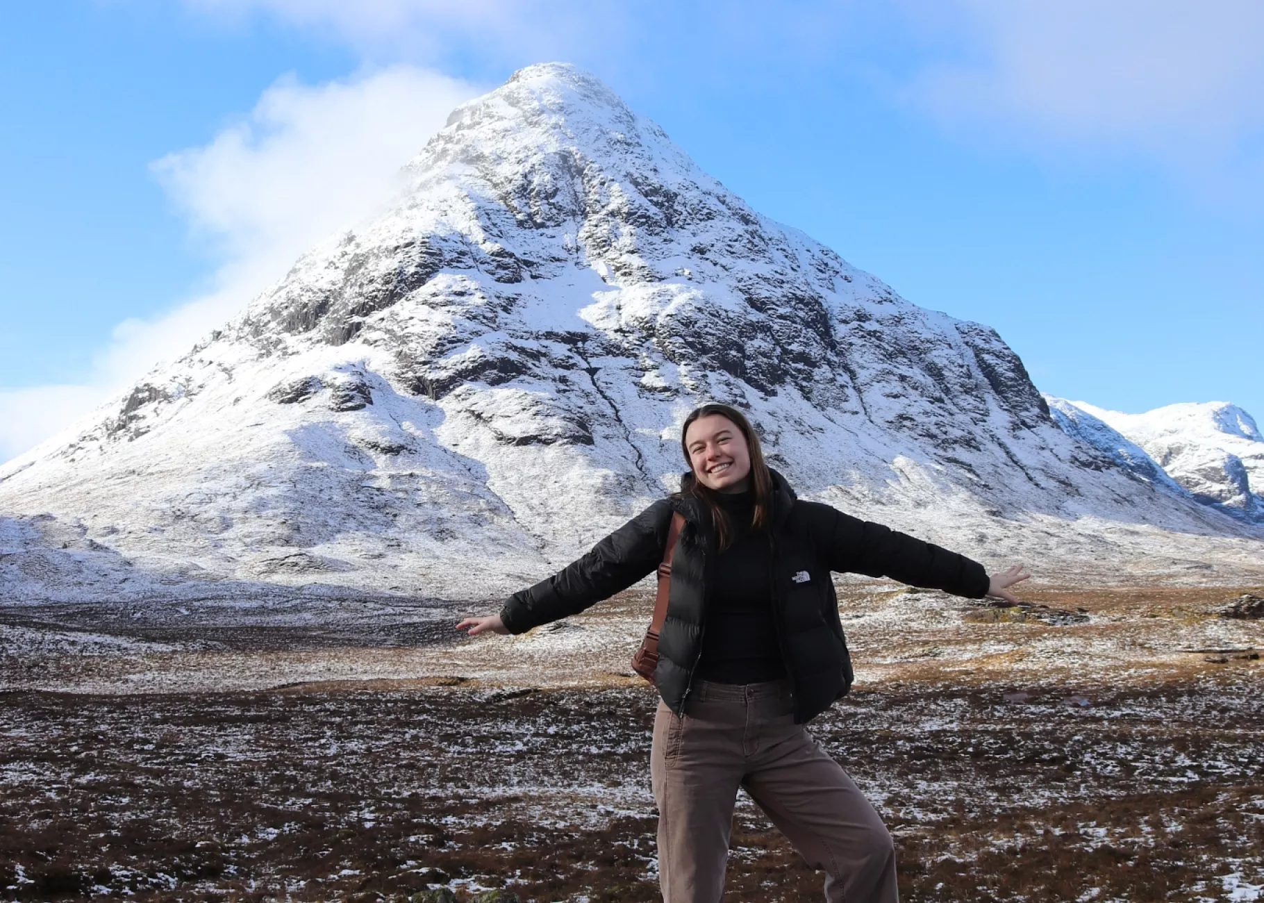 UofL student poses on a rock with a snowy mountain in the background. Scottish Highlands.