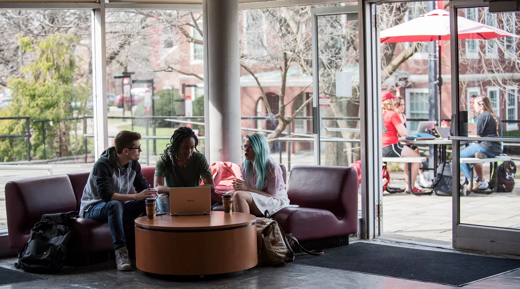 Three fine art students working together in the lobby of Schneider Hall