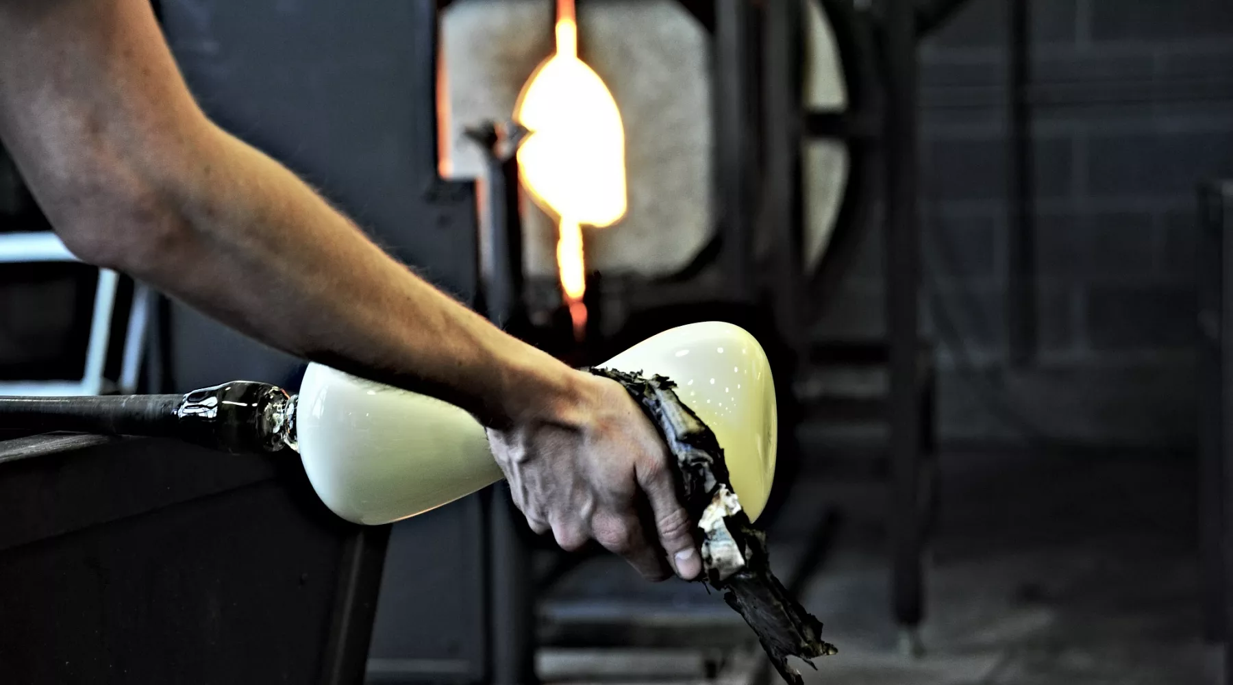 artist glassblowing in front of kilns