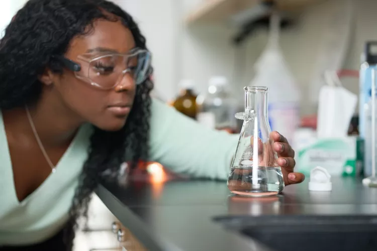 Female student performs chemistry experiment in a lab