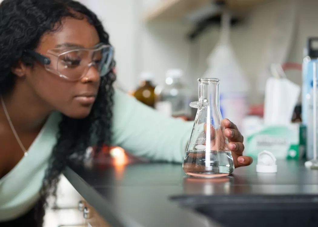 Female student performs chemistry experiment in a lab