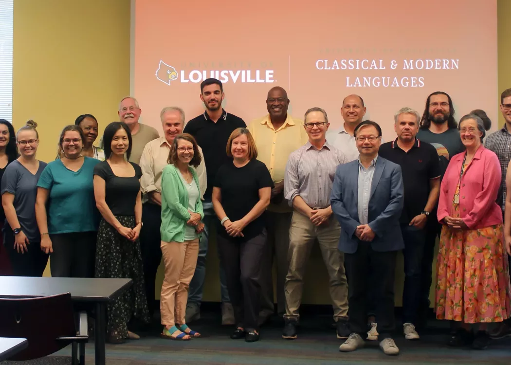 CML Faculty and Staff stands in front of a presentation screen displaying "Classical & Modern Languages" at the University of Louisville.