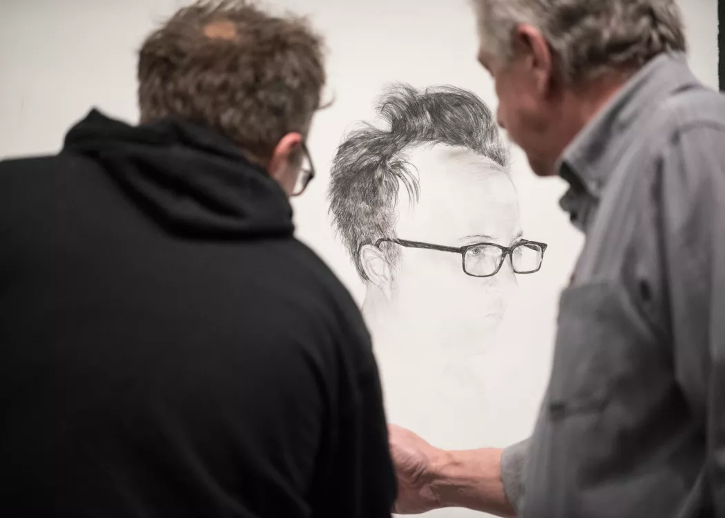 Student works on a self portrait with the help of his professor